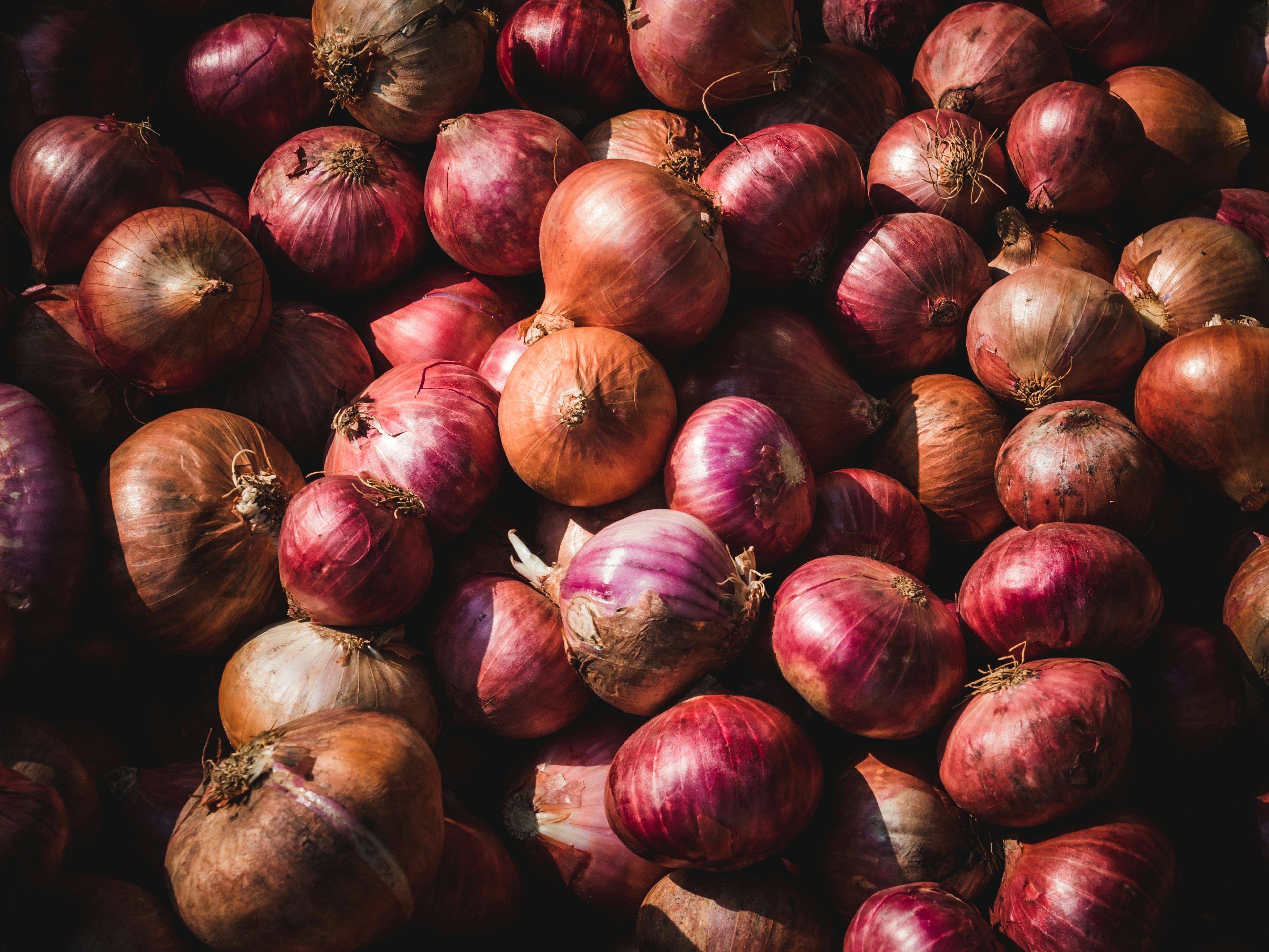 A large pile of red and brown onions